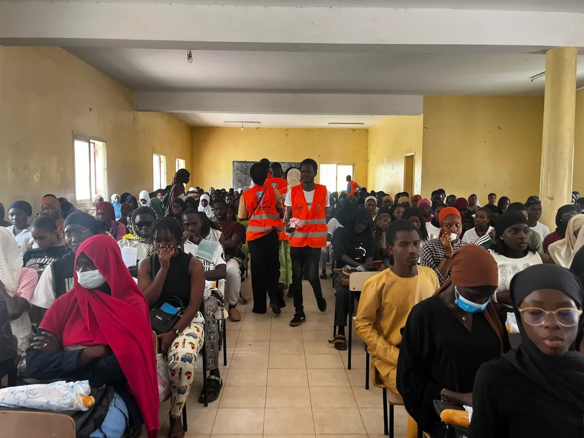 Salle comble, bénévoles en gilets orange distribuant les kits déjeuners
